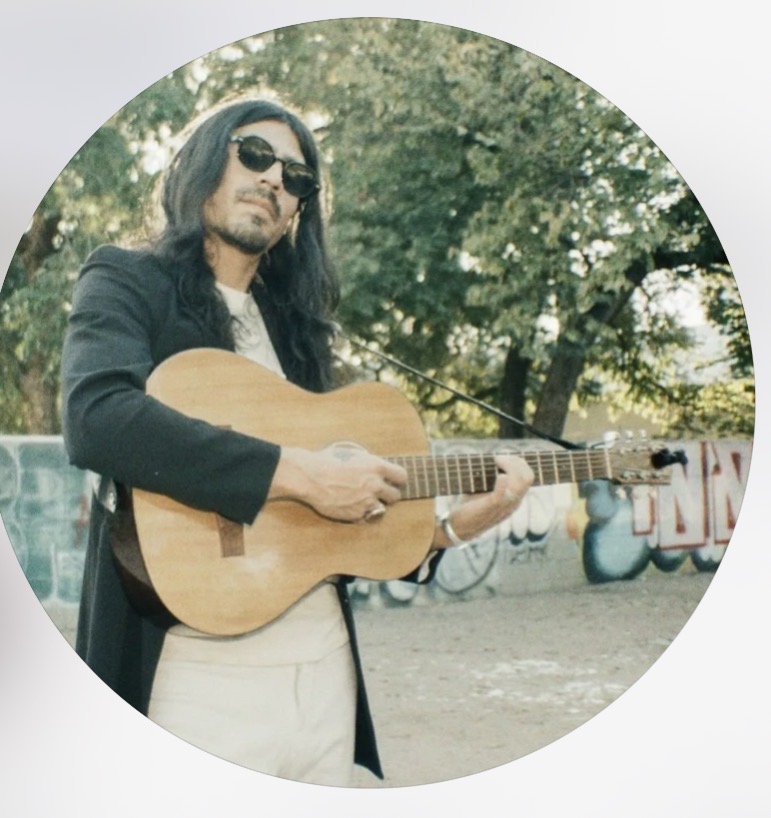 Portrait of Prieto Bosques wearing sunglasses and holding a guitar.